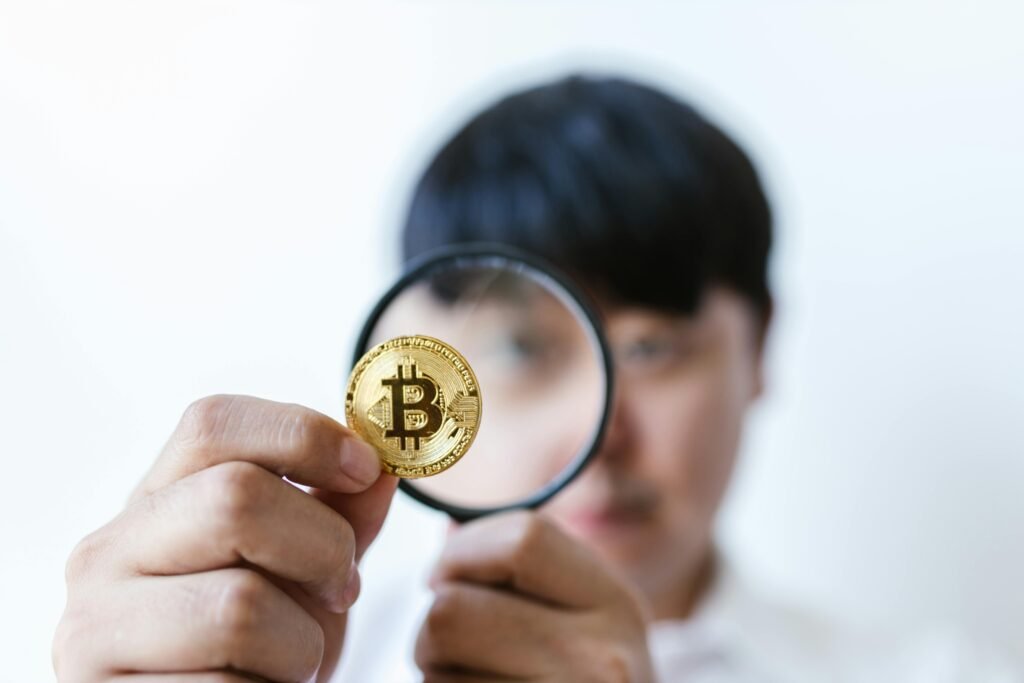 pexels photo 8370783 8370783 Close-up of a person examining a Bitcoin with a magnifying glass, highlighting cryptocurrency focus.