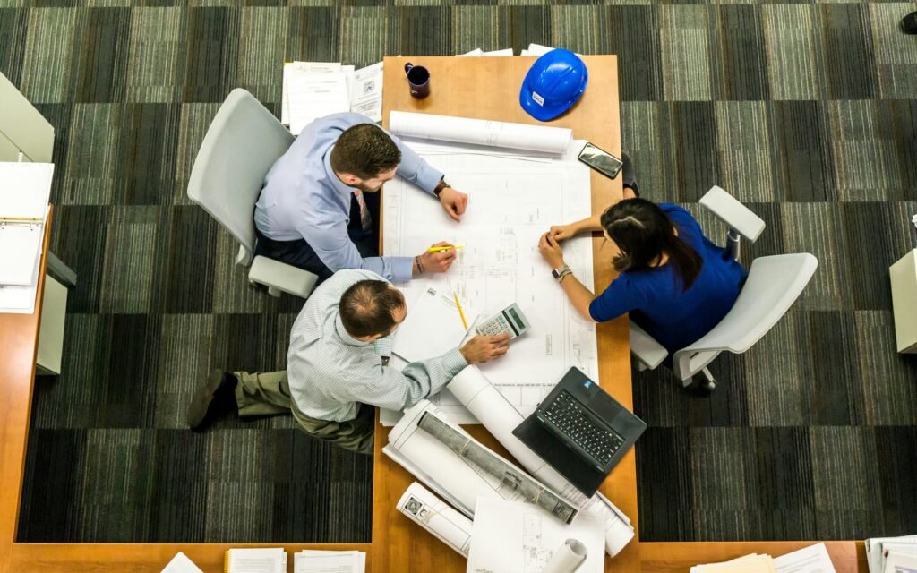 pexels photo 416405 416405 1 Top view of a team working on construction plans in an office setting.